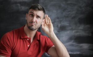 man with hand up to ear listening
