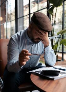 man at a coffee shop with hand over his face
