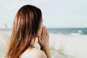 woman at the beach with praying hands 