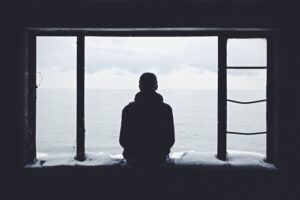 man looking out windy at a storm 