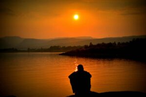 Man looking towards a lake at sunset